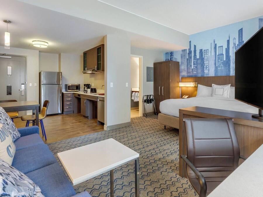 Ein Hotelzimmer mit Bett, Schreibtisch und einer Küchenzeile.