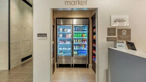 Un vestíbulo de hotel con un letrero que dice 'market' sobre un mostrador refrigerado lleno de bebidas y aperitivos.