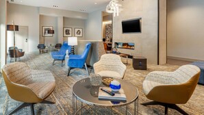 Una sala de estar moderna con un sofá, sillones, una mesa de centro y un televisor montado en la pared.