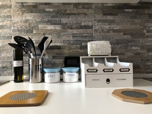 Kitchen features a clean layout with stainless steel containers and a spice rack for utensils.