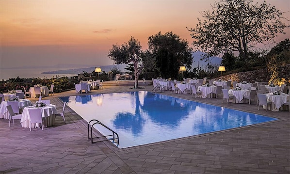 En säsongsöppen utomhuspool, parasoller och solstolar