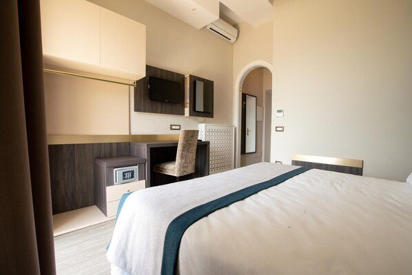 A hotel room with a large bed, a desk with a chair, a TV mounted on the wall, and a wardrobe. - San Lorenzo - Boutique Hotel & SPA (Lettere)