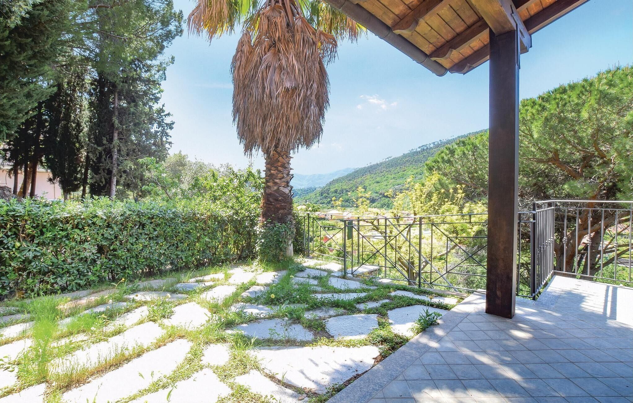 A paved pathway with stone tiles and grass patches, leading to a covered area with a metal railing.