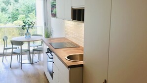 Una cocina moderna con una mesa de comedor redonda, armarios blancos y un amplio ventanal.