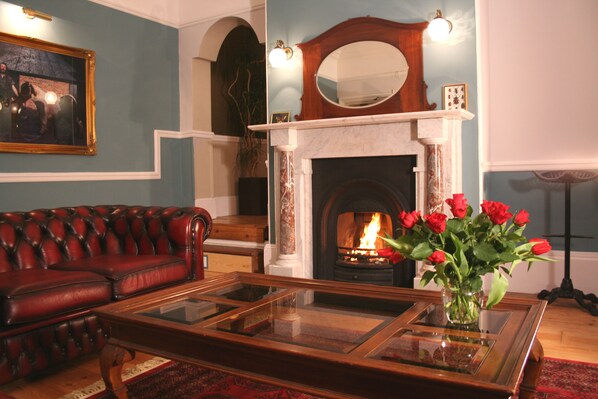 A living room with a fireplace, a red leather sofa, and a glass coffee table.