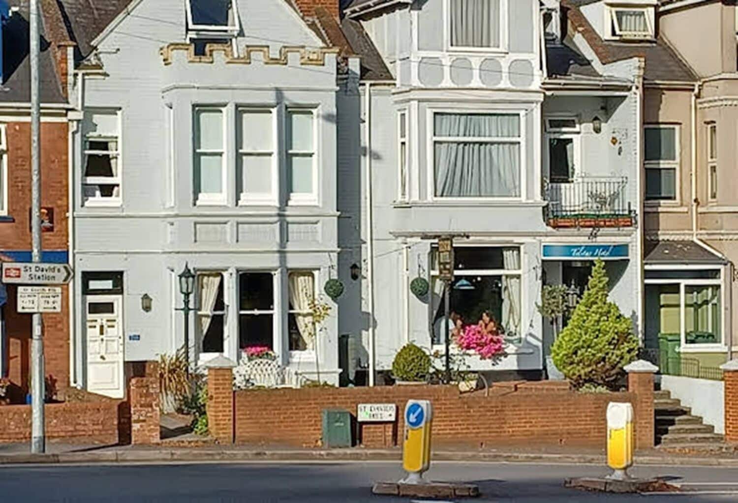 A row of white two-story houses with a shop on the ground floor.