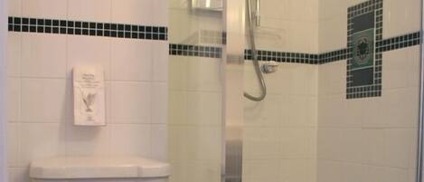 A bathroom with a toilet, a glass-enclosed shower, and a checkered floor.