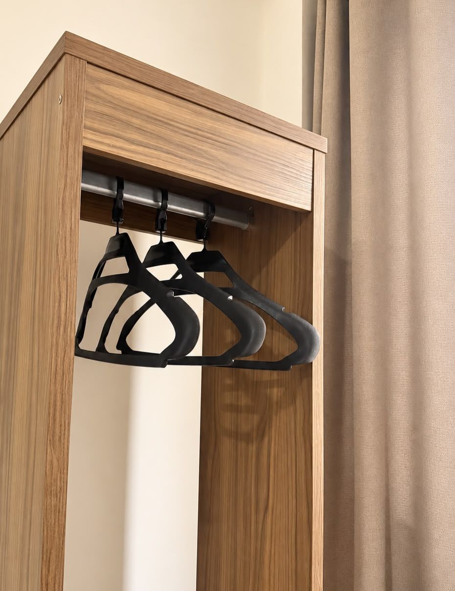 A wooden cabinet with a hanging rack for clothes.