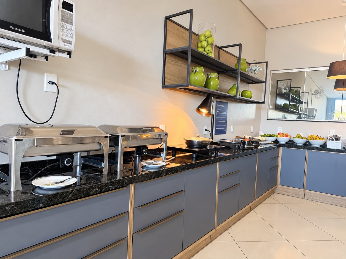 A modern kitchen with a built-in microwave, a buffet setup, and a fruit display.