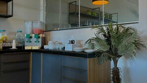 A modern kitchen with dark cabinetry, a large mirror, and pendant lighting. - Hotel Skalla (Teixeira de Freitas)