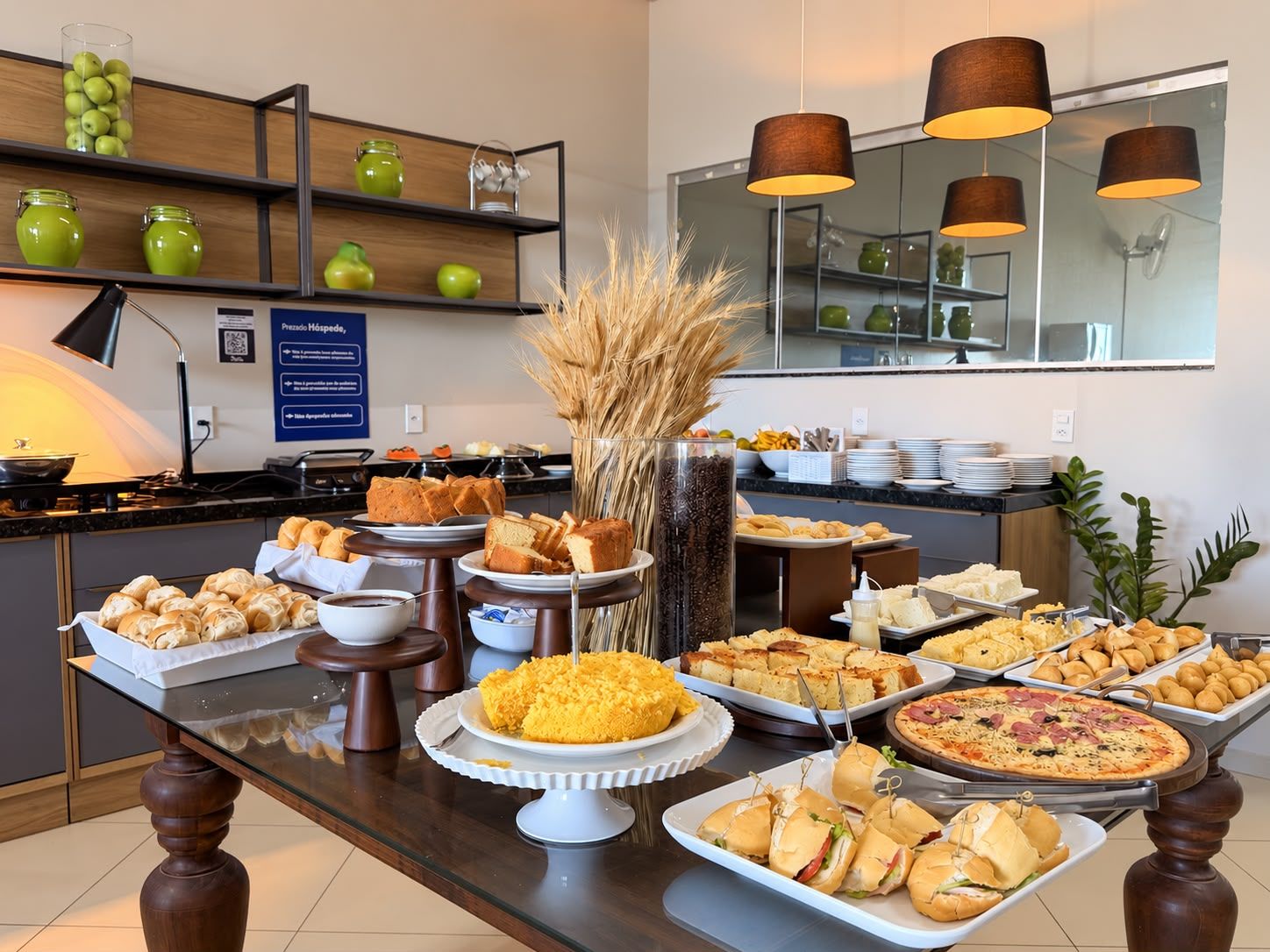 Montaje de bufé con diferentes alimentos, un espejo y un cartel que indica un servicio del hotel.