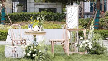 A garden setting with a table, chairs, and a mirror.
