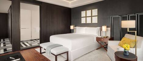 A modern hotel room with a large bed, bedside tables, a sofa, and a small table with a vase of flowers.