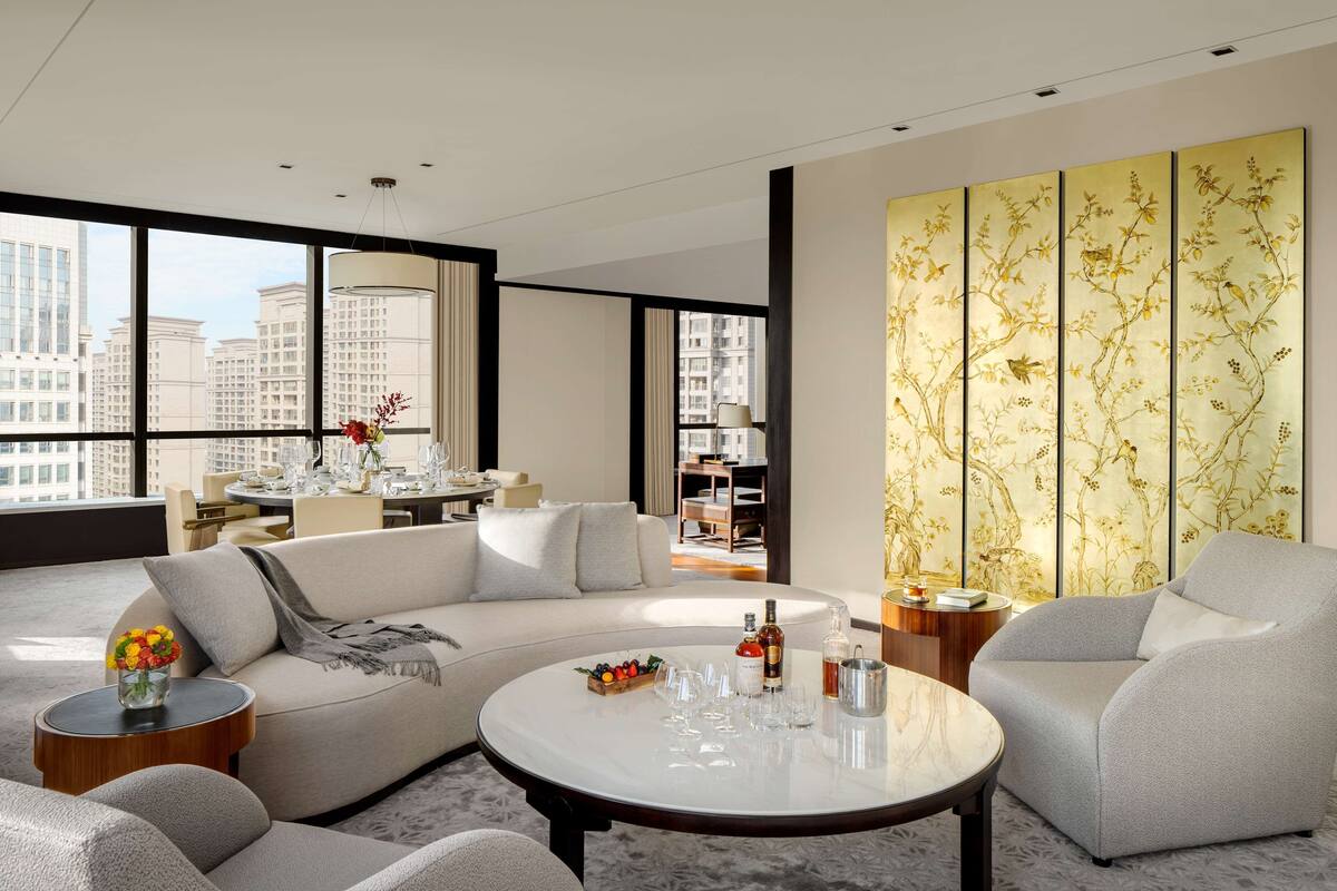 A modern living room with a sofa, armchairs, a coffee table, and a decorative wall panel.