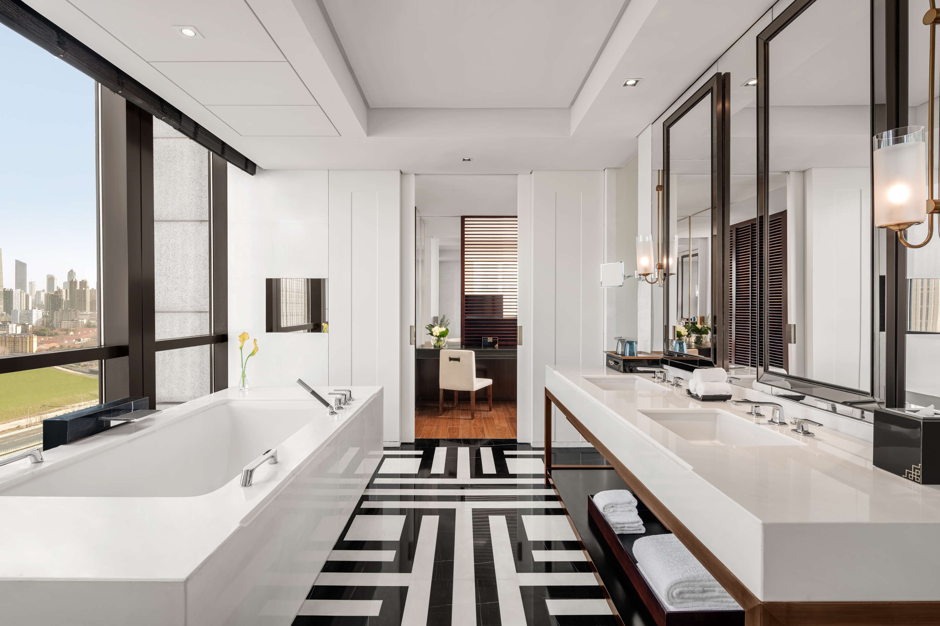 A modern bathroom with a large bathtub, two sinks, and a mirror.