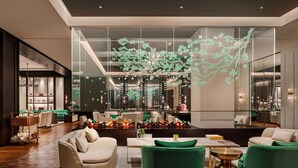 Un hall d’hôtel moderne doté d’un espace salon, d’une cheminée et d’une installation lumineuse décorative.