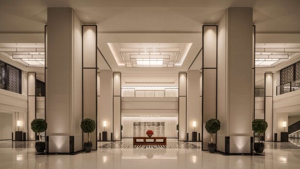 Un hall d’entrée spacieux, doté de hauts plafonds, de grandes colonnes et d’un espace salon central.