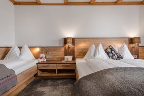 Habitación de hotel con dos camas individuales, cabeceros de madera, mesitas de noche con lámparas y un pequeño adorno en una de las camas.