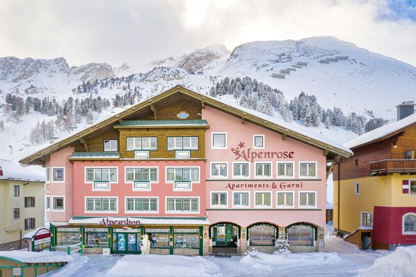 Un edificio de varios pisos con un letrero que dice 'Alpenrose Apartments & Garni'.