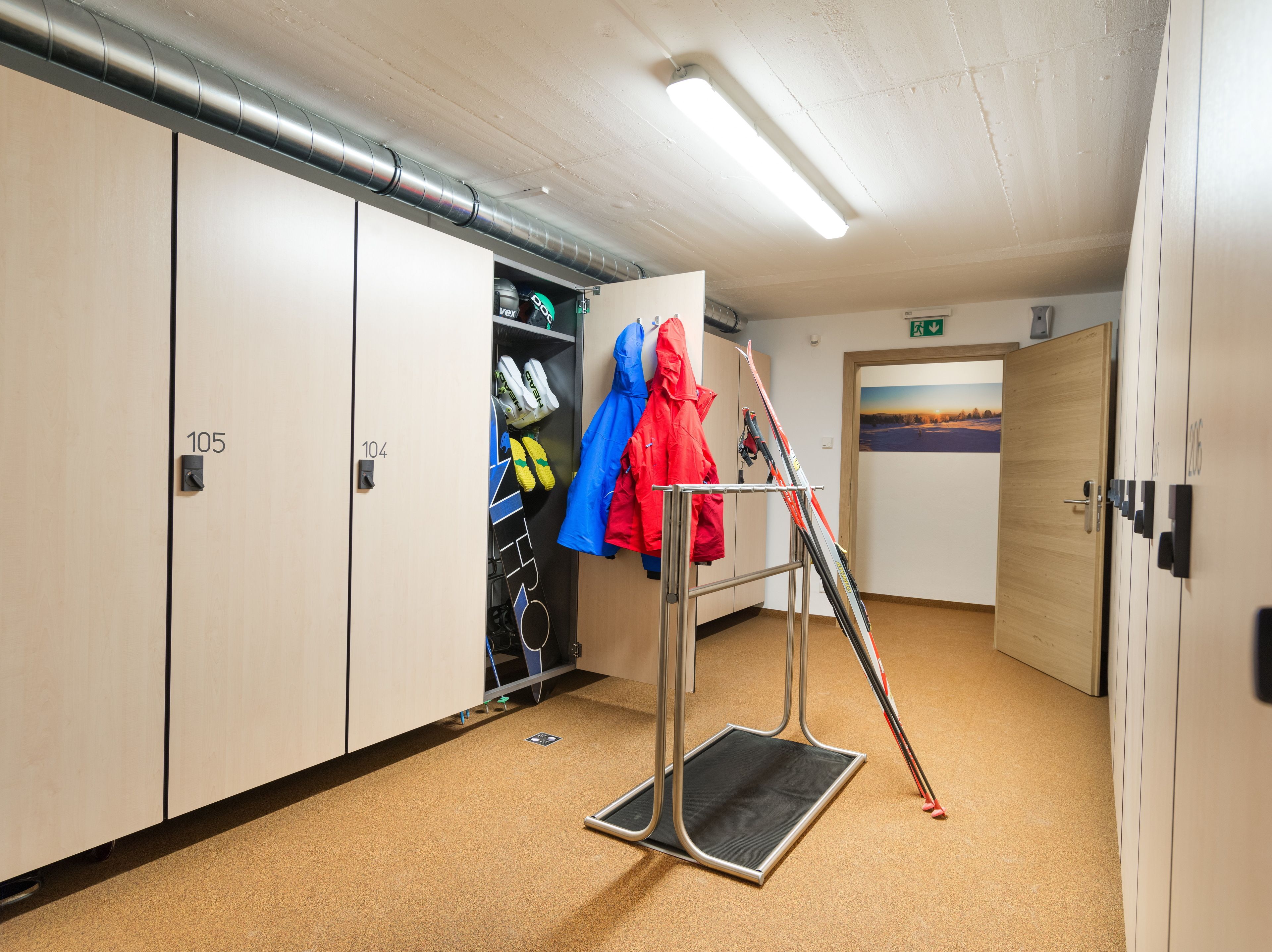 A locker room with numbered lockers, a shoe rack, and a ski rack.