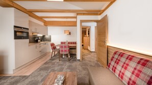 A modern kitchen with wooden beams, a dining area with a plaid sofa, and a cozy seating arrangement. - Apartments  Garni Alpenrose (Tweng)