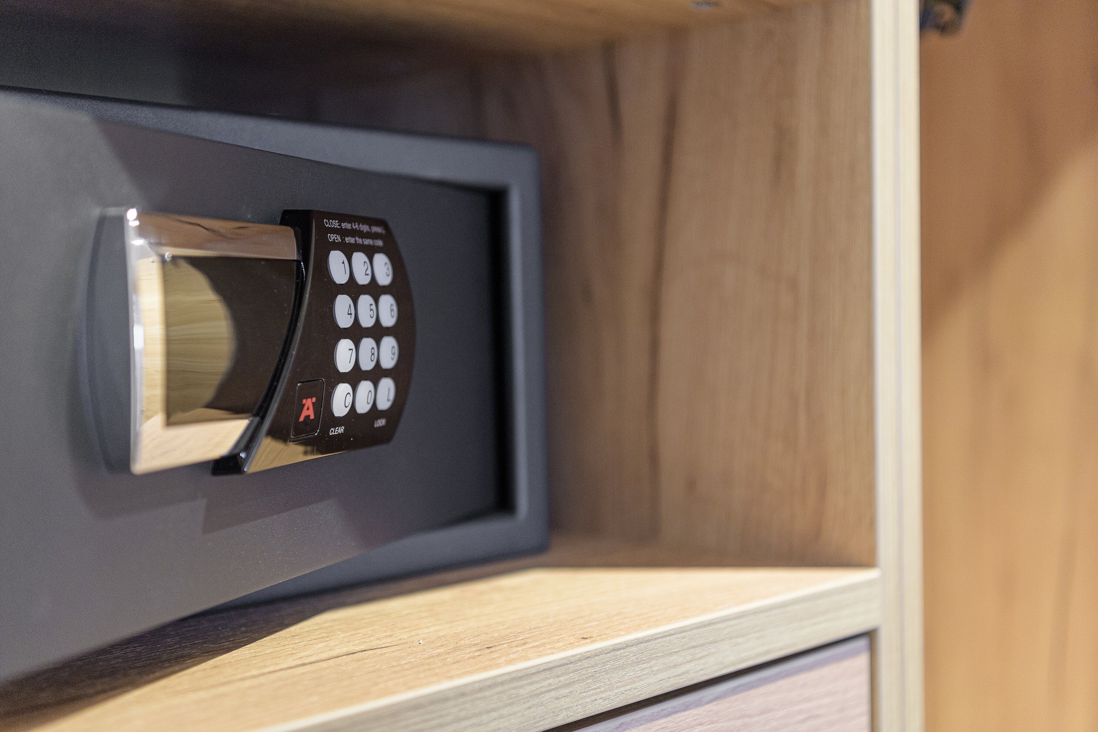 A microwave with a digital keypad and a small display screen, mounted on a wooden cabinet.