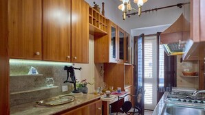 A kitchen with wooden cabinets, a sink, a stove, and a dining area with a chair. - B&B IreneMarchese - Gluten Free (Taviano)