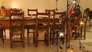 A dining area with wooden tables and chairs, a glass-top table with candles, and a decorative metal piece. - B&B IreneMarchese - Gluten Free (Taviano)