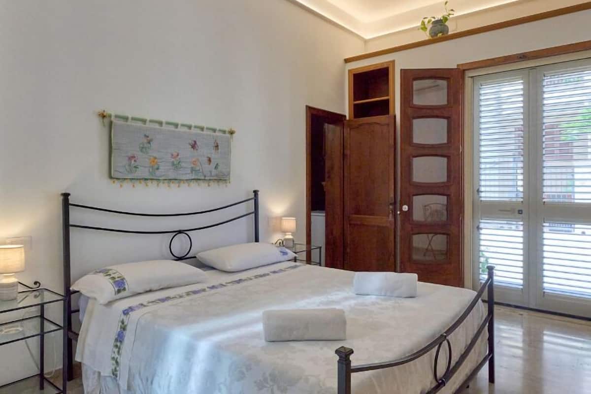 Ein Schlafzimmer mit einem Bett, Nachttischen, einer Wanddekoration und einer Schiebetür.