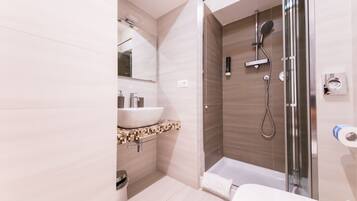 Une salle de bain moderne avec une douche à parois de verre, un lavabo blanc et des toilettes.