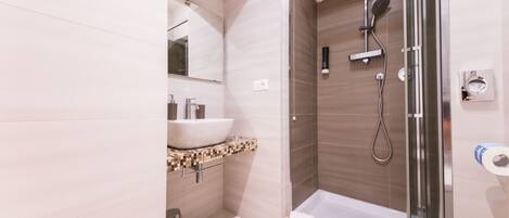 Une salle de bain moderne avec une douche à parois de verre, un lavabo blanc et des toilettes.