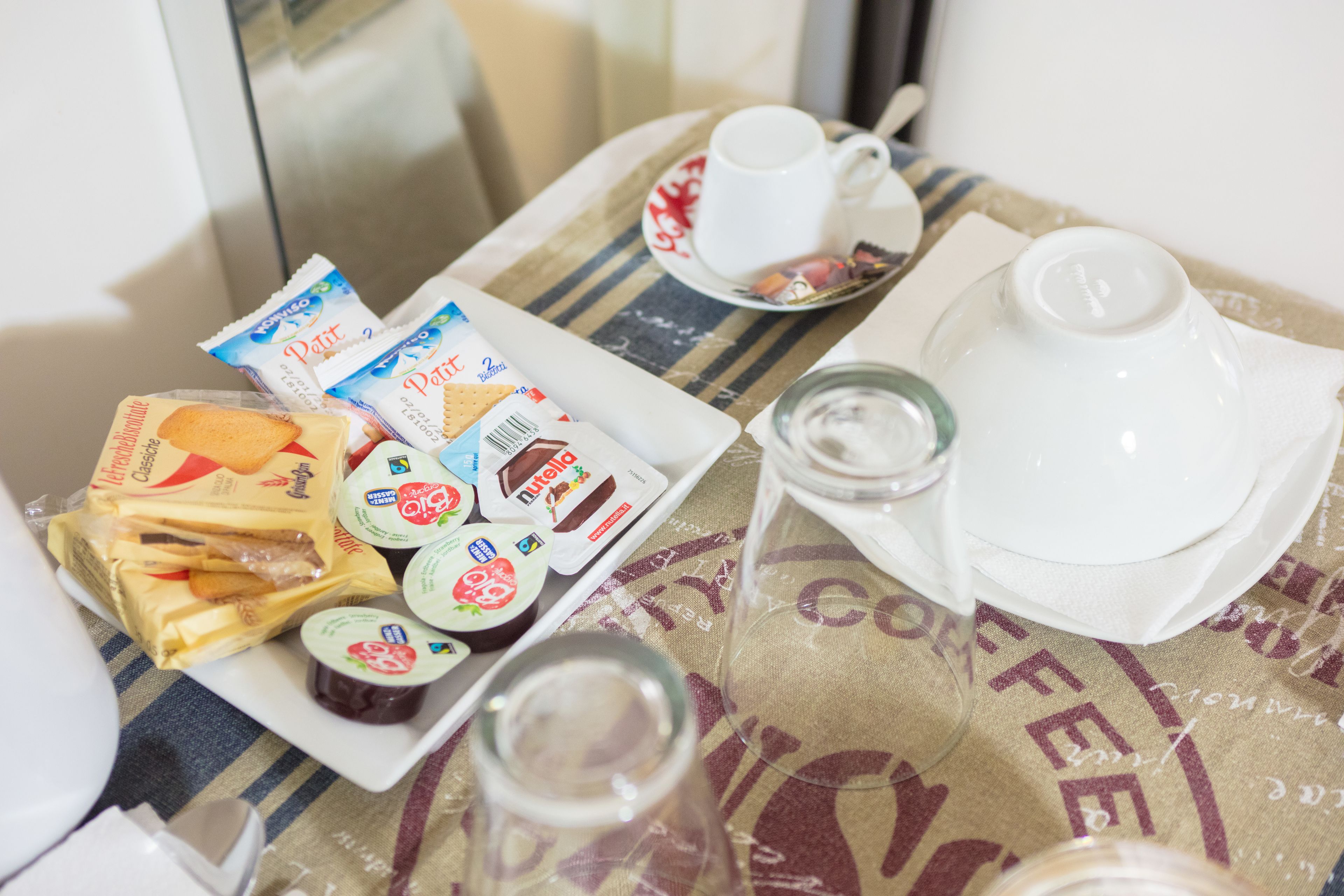 A breakfast table with a coffee cup, a teapot, and various food items including cheese and yogurt.