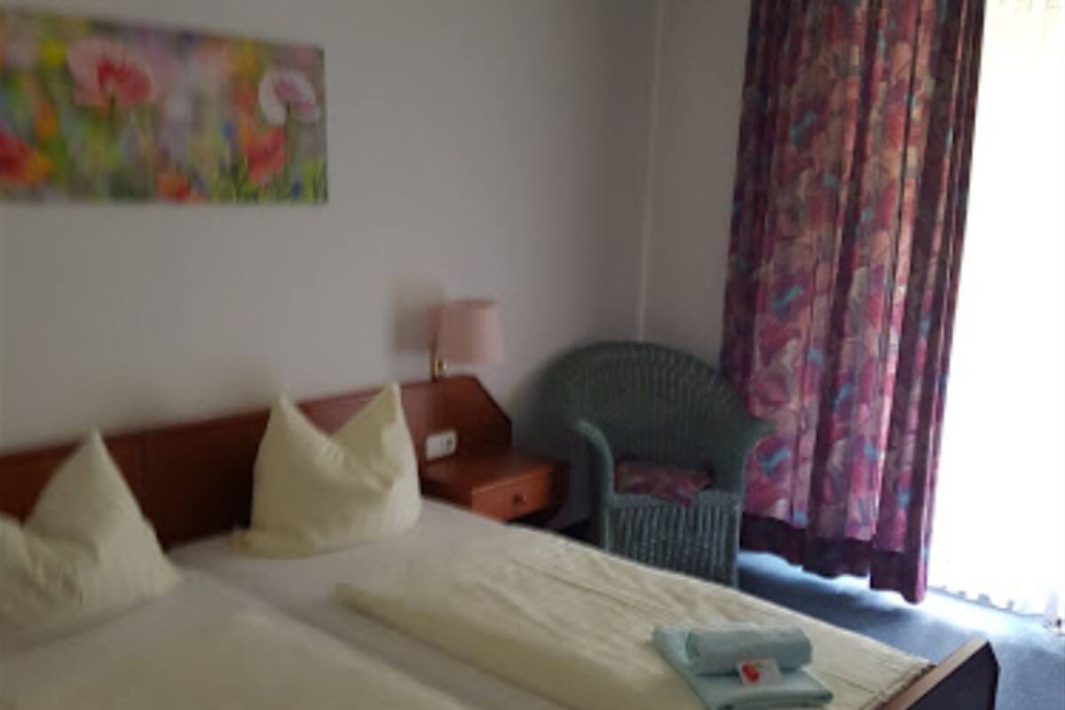 Ein Hotelzimmer mit zwei Betten, einem Sessel, einem kleinen Tisch und einem Bild an der Wand.