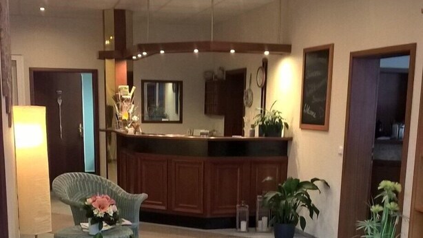 A hotel lobby with a reception desk, seating area, and potted plants. - Hotel Mühlbergblick (Frankenblick)