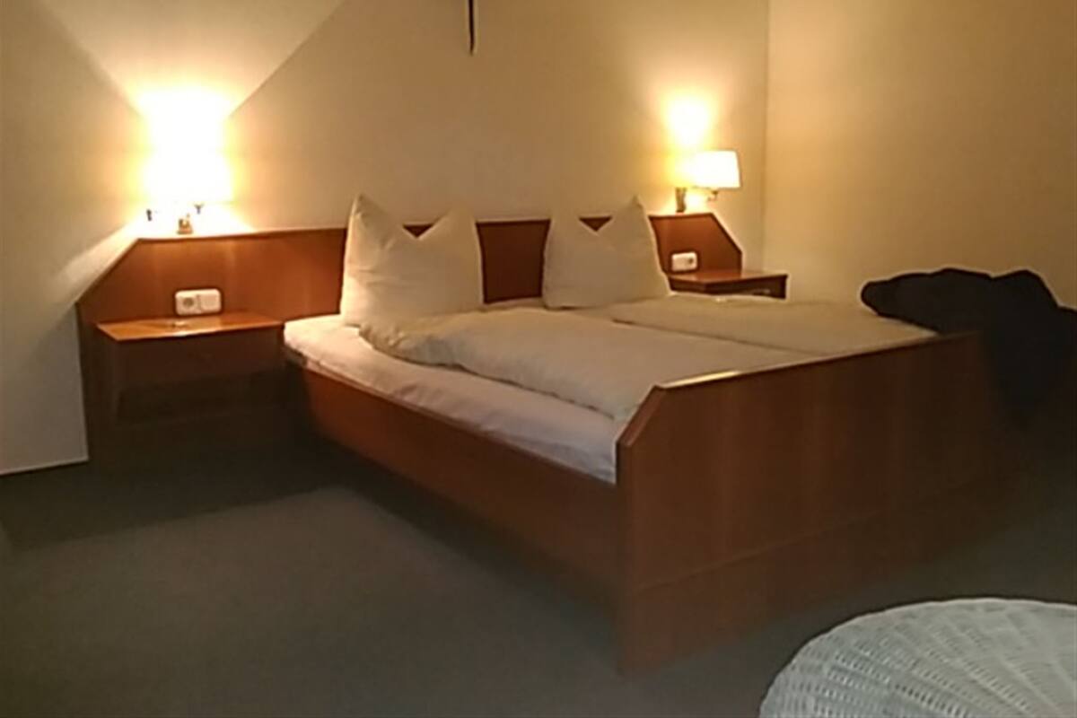 Ein Standard-Hotelzimmer mit einem Einzelbett, zwei Nachttischen und zwei Wandlampen.