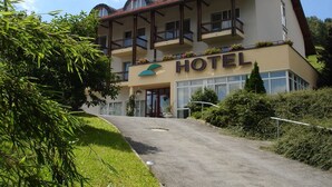 A hotel with a modern design, featuring a prominent balcony on the second floor, a well-maintained lawn, and a clear sky. - Hotel Mühlbergblick (Frankenblick)