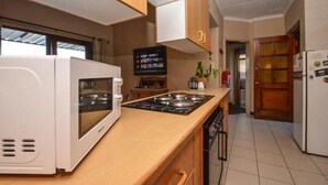 A compact kitchen with a microwave, stove, and a small TV on the counter. - Quail's Nest (Roodepoort)