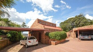 A brick building with a carport and a paved driveway. - Quail's Nest (Roodepoort)
