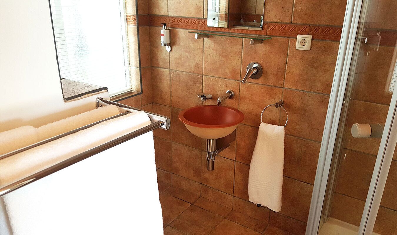 Une salle de bain équipée d’un lavabo, d’un miroir, d’un porte-serviettes et d’une zone douche.