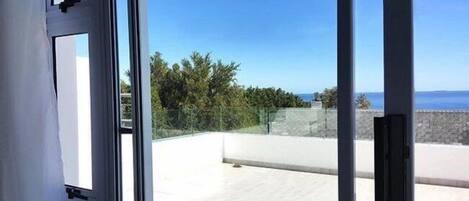 A view from a balcony with a clear sky and ocean in the background.