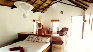 A bedroom with a bed, a chair, a small table, and a window. - Barefoot Lodge and Safaris - Malawi - Campsite (Chitedze)