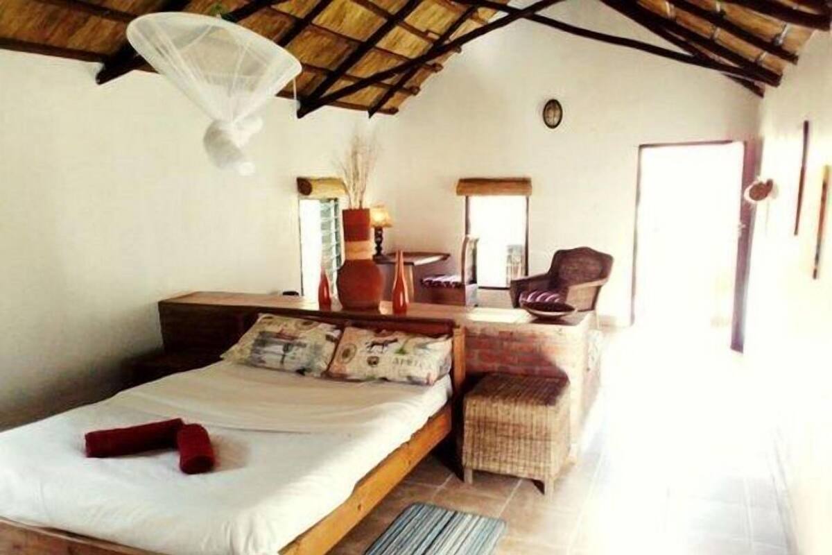 A bedroom with a bed, a chair, a small table, and a window.