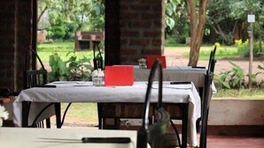 A dining area with a table set for two, a red napkin, and a white tablecloth. - Barefoot Lodge and Safaris - Malawi - Campsite (Chitedze)