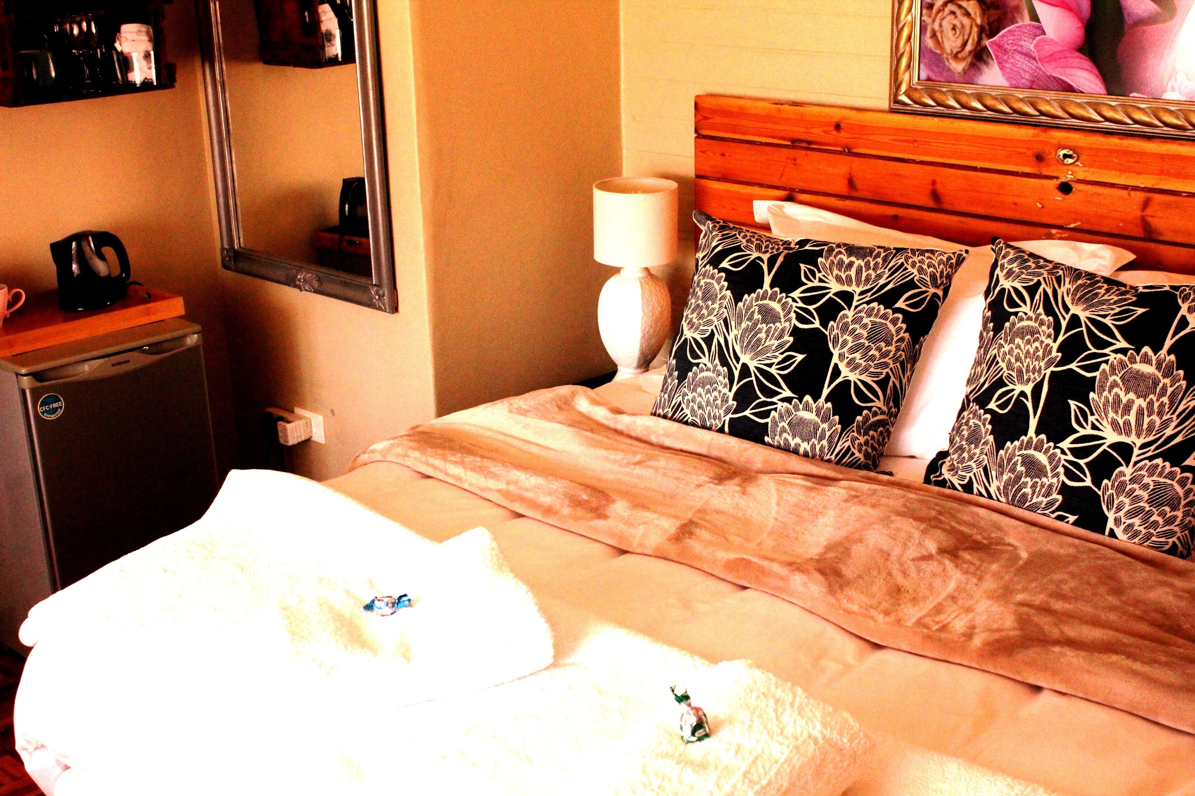 Ein Hotelzimmer mit Bett, Nachttisch, Lampe, Spiegel und Kommode.