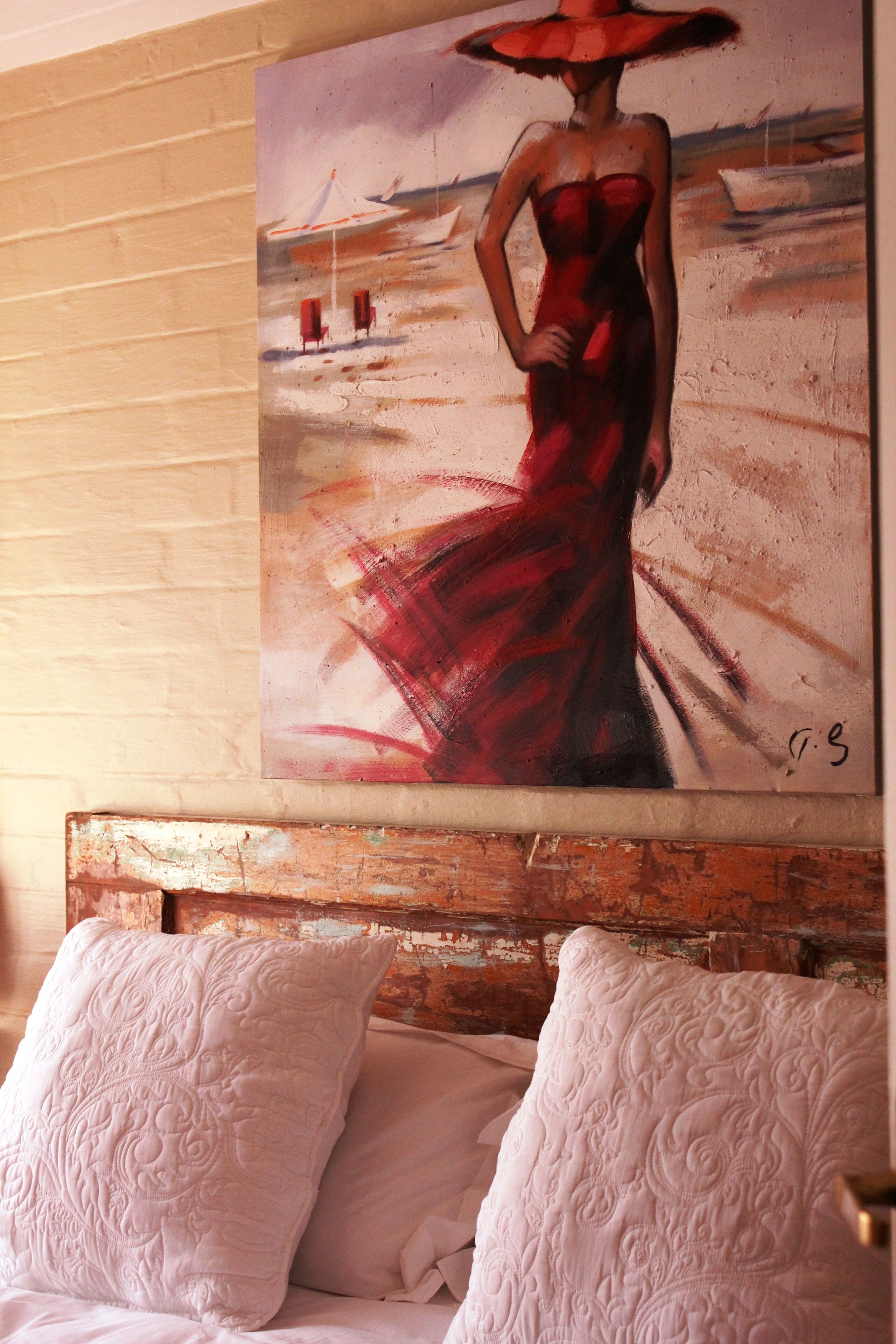 A painting of a woman in a red dress on a bed with white pillows.
