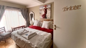 A hotel room with a bed, a chair, a painting, and a sign on the wall. - The-Ark B & B (Pearly Beach)