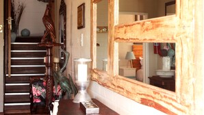 A staircase with a wooden railing, a large mirror, and a decorative vase on a table. - The-Ark B & B (Pearly Beach)