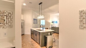A modern kitchen with a central island, stainless steel appliances, and a pendant light.