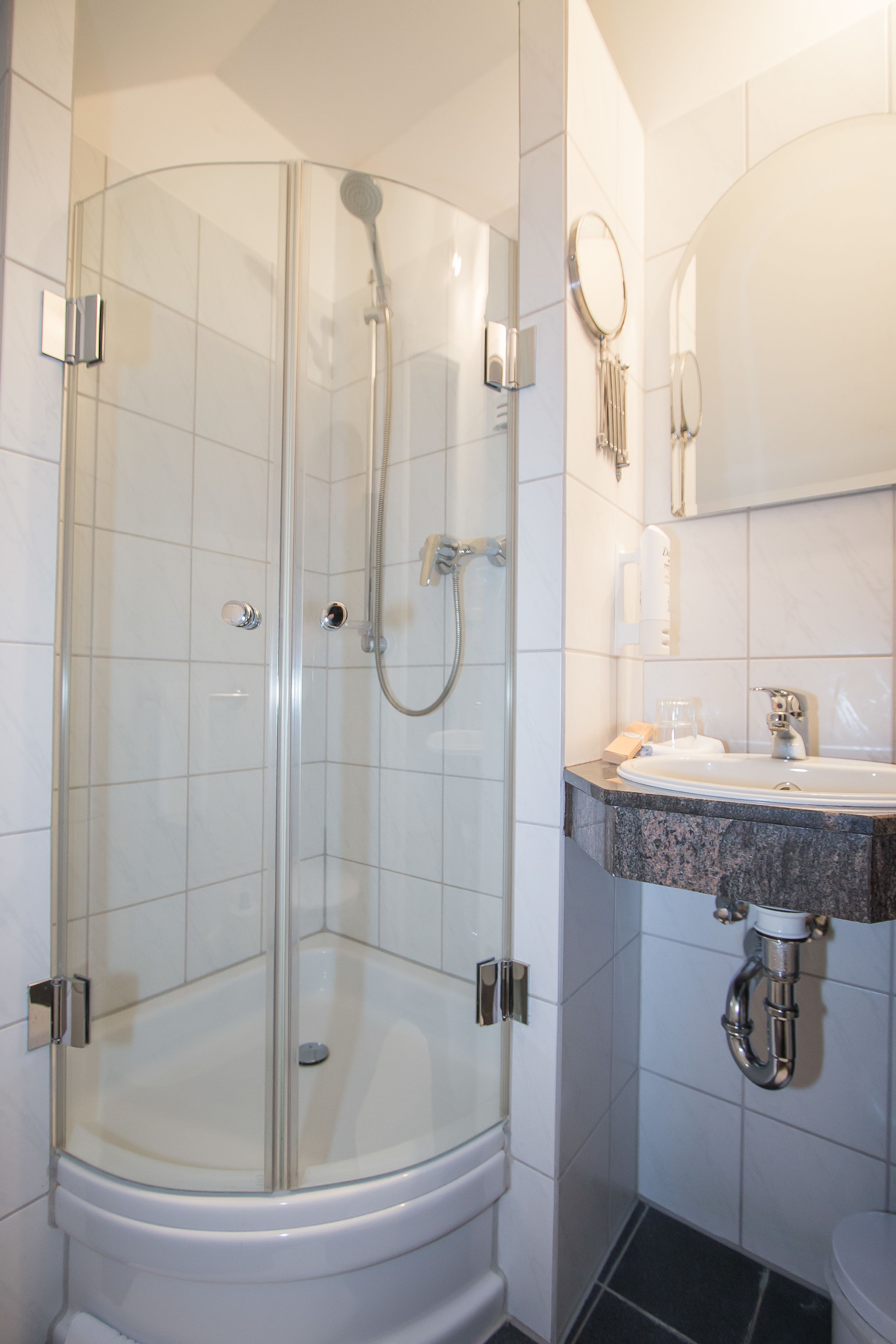 A glass-enclosed shower with a white sink and mirror.