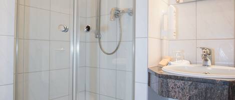A glass-enclosed shower with a white sink and mirror.